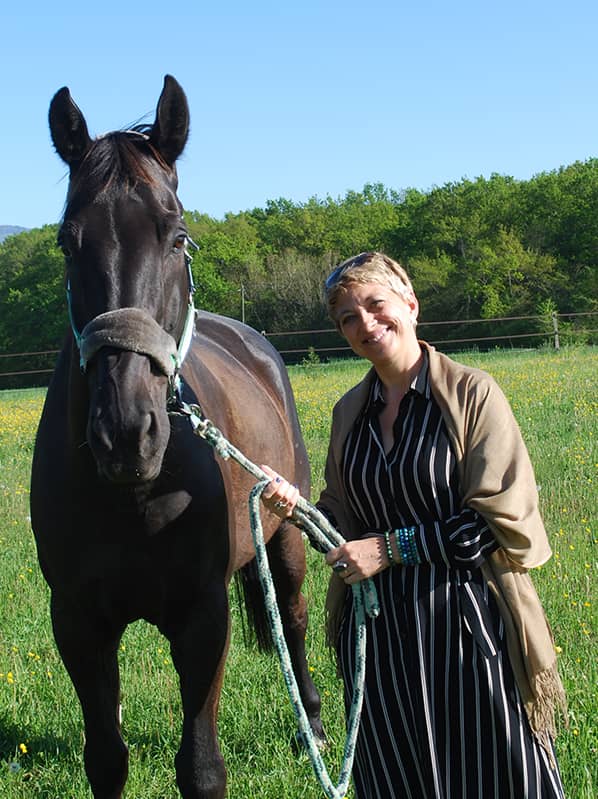 Femme souriante avec un cheval noir.